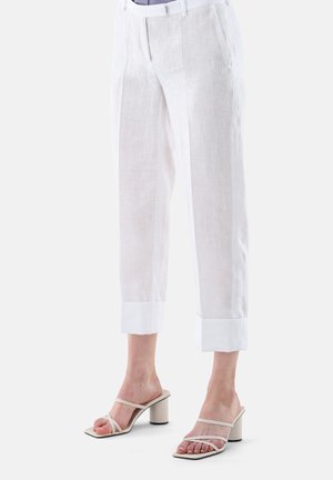 Weiße Leinen-Culottes mit glatter Textur und umgeschlagenen Säumen, kombiniert mit beigen Sandalen mit Absatz und dünnen Riemen.