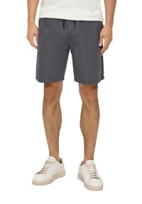 Grau Shorts mit einer lockeren Passform, ausgestattet mit einem elastischen Bund und Kordelzug. Kombiniert mit weißen Sneakers, die ein sauberes Design zeigen.