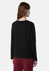 Top nero a maniche lunghe realizzato in materiale morbido, con scollo rotondo e vestibilità comoda. Il retro è semplice e senza cuciture, design minimalista.