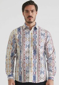 Chemise à manches longues pour homme en tissu blanc, ornée de motifs géométriques en bleu, rouge et or. Fini avec un col classique et une fermeture par boutons.