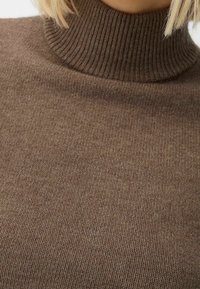 Maglione a collo alto marrone lavorato a maglia con una texture a coste e un design aderente. Presenta un collo alto e una finitura del tessuto liscia e morbida.