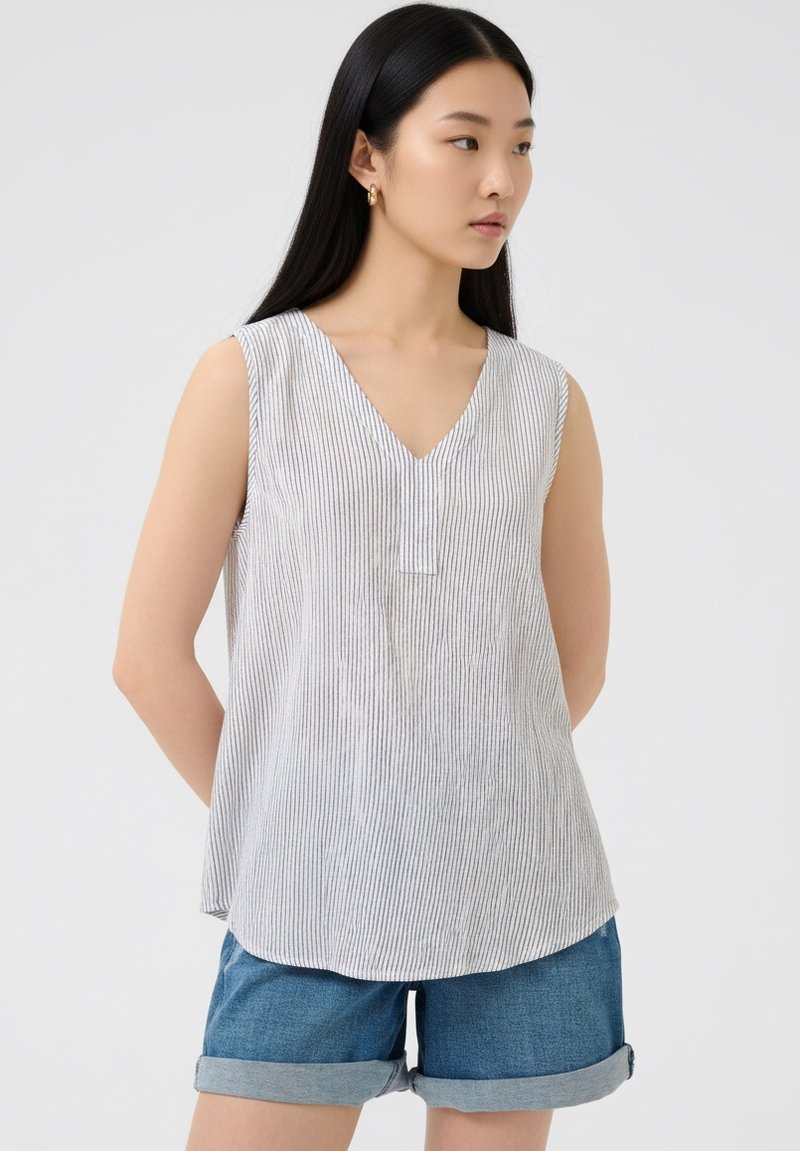 Sleeveless striped top in light gray and white, with a V-neckline and stitched detailing, paired with rolled-up denim shorts.