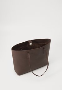 Brown leather tote bag with a textured surface, open top, two handles, and an interior pocket. Features a snap closure for security.