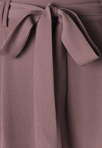 Teksturowana, fioletowawa tkanina z przewiązanym paskiem w talii. Gładka powierzchnia z delikatnym połyskiem, wyposażona w płaski pas i przeszycia dekoracyjne.