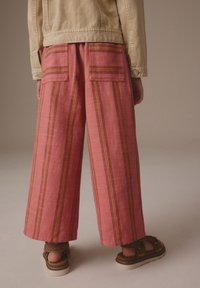 Losse, lichtroze broek met verticale strepen in donkere kleuren, voorzien van twee achterzakken en een textuurstof.