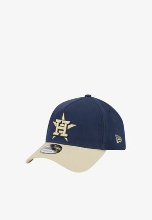Blue baseball cap with beige bill, featuring embroidered gold "H" logo and star design on front, made from textured fabric. Adjustable fit.