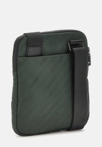 Borsa a spalla in nylon verde con accenti neri, forma rettangolare, texture imbottita e marchio embossato sul davanti. Manico rimovibile.