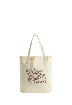 Crèmekleurige draagtas met handvatten, voorzien van een bruine kreeftenillustratie en de tekst "Gant Seaside" geborduurd op de voorkant.