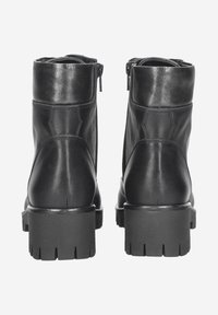 Bottines noires en cuir avec une finition lisse, dotées d'une fermeture éclair latérale, d'une semelle épaisse robuste et de subtils détails de couture à l'arrière.