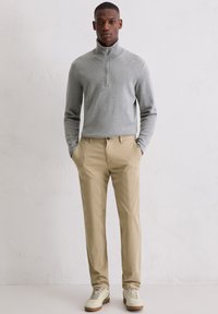 Gray zip-up sweater, beige chinos, and cream sneakers. Smooth texture, tailored fit, and minimalistic design with no visible patterns or logos.