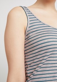 Top de tirantes a rayas en tonos azul claro y rosa, con una textura acanalada y tirantes anchos, que resalta un diseño ajustado.