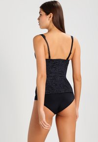 Juoda gėlėta maudymosi tankini viršutinė su reguliuojamomis petnešėlėmis, derinama su tamsiomis bikini kelnaitėmis. Lygus paviršius su prigludusia forma.