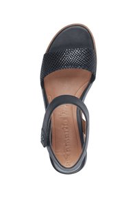 Schwarze Sandale mit einem geflochtenen Leder-Obermaterial, verstellbarem Riemen und einer gepolsterten beigen Innensohle. Flache Sohle mit runder Zehenpartie.