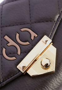 Bolso de mano de cuero negro acolchado que presenta un cierre metálico en tono dorado con patrones geométricos y un acento circular central.