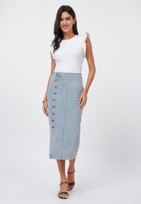 Hvit ribbet tank topp med volanger i ermene, kombinert med en lys blå denim blyantkjole med knappelukking foran og sideslitt.