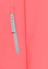 Tessuto color corallo con una texture liscia, caratterizzato da una tasca con zip argentata sul lato sinistro e dettagli di cucitura in contrasto.