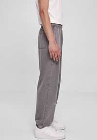 Grå sweatpants med en afslappet pasform, elastisk talje, sidelommer og en glat tekstur, parret med hvide sneakers.