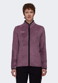 Chaqueta de forro polar morado con un acabado texturizado, collar alto y cremallera negra. Presenta el logo de Mammut en el pecho y bolsillos laterales.