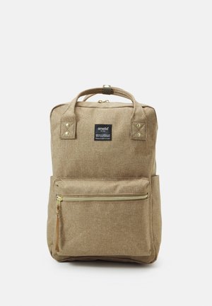 Sac à dos beige rectangulaire avec poche frontale zippée, double poignée supérieure, et étiquette noire portant la mention "anello" en texte blanc.