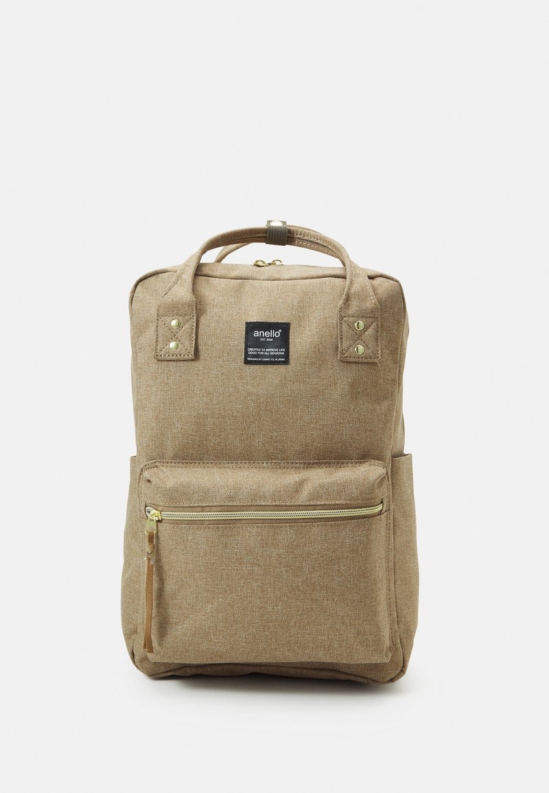 Sac à dos beige rectangulaire avec poche frontale zippée, double poignée supérieure, et étiquette noire portant la mention "anello" en texte blanc.