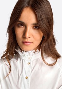 Weißes Hemd mit Knopfleiste und hohem, mit Spitze eingefasstem Kragen. Verfügt über einen strukturierten Stoff und drei Knöpfe auf der Vorderseite, mit einem schlichten Design.