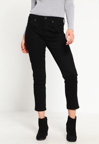 Černé slim-fit džíny se klasickým pětimístným designem, zapínáním na knoflík a zkrácenou délkou s viditelnými švy.