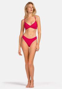 Jasnoróżowy bikini z topem z przekręconym przodem i wysokim stanem. Gładki materiał z cienkimi ramiączkami i minimalnym zakryciem. Bez wzorów i dodatkowych elementów.