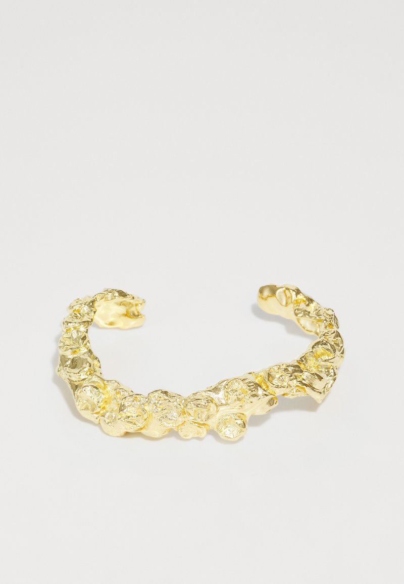 Χρυσό περιβραχιόνιο με υφή που διαθέτει οργανικά, στρογγυλά σχήματα και ανώμαλες, ανυψωμένες λεπτομέρειες σε όλο το μήκος του.