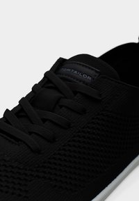 Μαύρο πλεκτό αθλητικό παπούτσι με κορδόνια και υφή σχεδίου, που δείχνει την ετικέτα της μάρκας Tom Tailor στη γλώσσα του παπουτσιού.