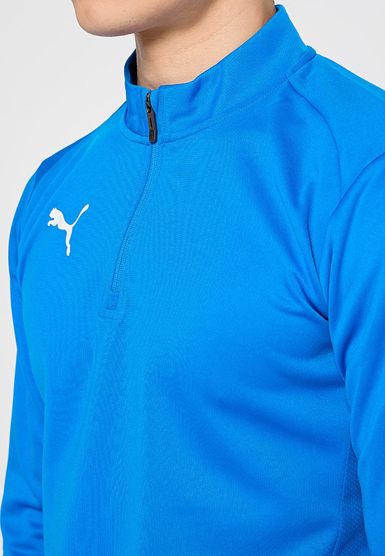 Sudadera de manga larga con cremallera de un cuarto en tejido azul brillante. Presenta un alto cuello y un logo blanco de Puma en el pecho. Textura suave.