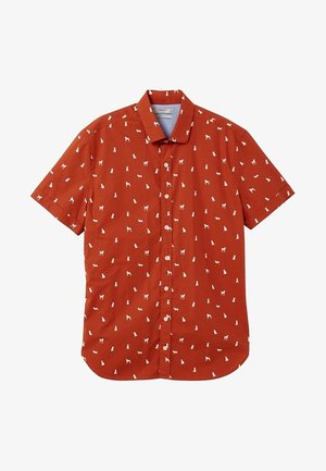 Chemise à manches courtes couleur orange rouille avec des silhouettes blanches de chiens réparties uniformément sur le tissu et un col pointu.