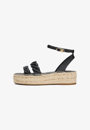 Sandales espadrilles noires avec des lanières torsadées, une plateforme enveloppée de jute et une boucle à la cheville. Comprend une semelle texturée et un dessus en cuir lisse.
