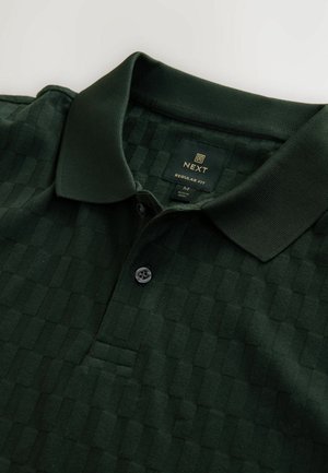 Camisa polo de color verde oscuro con un sutil patrón de cuadros, cuello tipo polo y cierre de dos botones. Fabricada en tejido texturizado.