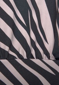 Tessuto a righe zebrate con onde alternate nere e beige chiaro, dalla texture liscia e con una lucentezza sottile. Dettaglio arricciato nella parte inferiore.