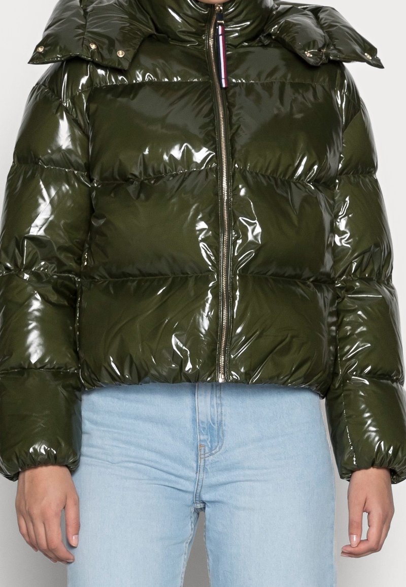 Skinnende olivengrøn pufferjakke med høj krave og lynlåsfront. Har et cropped design og vandrette quiltede sektioner.