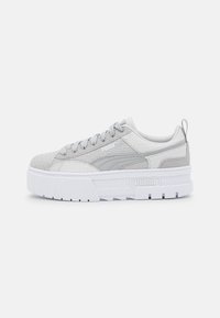 Sneaker grigio chiaro con tessuto testurizzato e finiture lisce. Presenta una suola bianca spessa, lacci rotondi e un tassello sul tallone.
