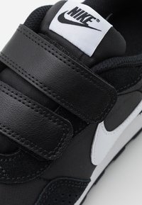 Sneakers Nike neri con un design elegante, fasce in velcro e il logo swoosh bianco prominente sul lato, con una finitura in materiale testurizzato.