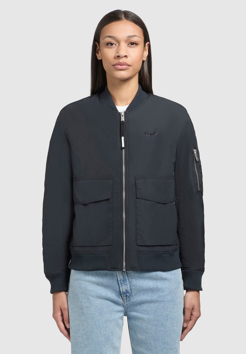 Tamno plavi bomber jakna s dva velika prednja džepa, džepom sa zatvaračem na rukavu, rebrastim manžetama i minimalnim logotipom na grudima.