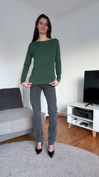 Πράσινο πουλόβερ με μακριά μανίκια και φαρδύ λαιμόκοψη, συνδυασμένο με γκρι παντελόνια με στενή γραμμή και μαύρα ψηλοτάκουνα παπούτσια, παρουσιάζοντας απαλή υφή.