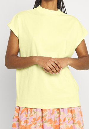 Citron gul bomuld t-shirt med høj hals, korte kapærmer og en afslappet pasform, kombineret med et blomsterprintet skørt.