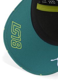 Gorra color teal con visera negra en contraste. Presenta la impresión amarilla "518" y el logotipo. Textura suave con costuras visibles y diseño perforado.