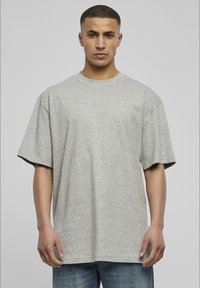 Grå bomull T-skjorte, oversized passform, korte ermer, rund hals, glatt tekstur, ensfarget, enkel design, brukt med blå jeans.