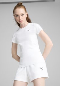 Witte getailleerde T-shirt en korte broek van katoenmix, met een klein zwart Puma-logo op de linkerborst en korte mouwen.