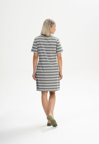 Gestreiftes Kleid in Grün und Lavendel, kurze Ärmel, lockere Passform, knielang, aus weichem Stoff mit einfachem Design. Flache grüne Schuhe abgebildet.