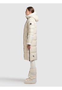 Lång beige vadderad jacka med huva, med dragkedja, texturerad kant, sidofickor och en logotyp på ärmen.