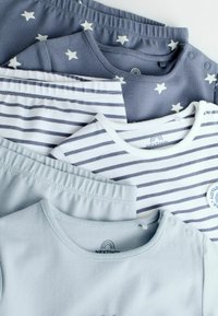 Quatre ensembles de vêtements pour bébés pliés, comprenant un imprimé étoiles bleues, des rayures bleues et blanches, des hauts unis bleu clair, et des bas rayés assortis.