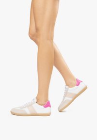 Weißes Sneakers mit rosa Fersenakzenten, beigen Überzügen und strukturierten Gummisohlen, ausgestattet mit Schnürdesign und seitlichen Mesh-Einsätzen.