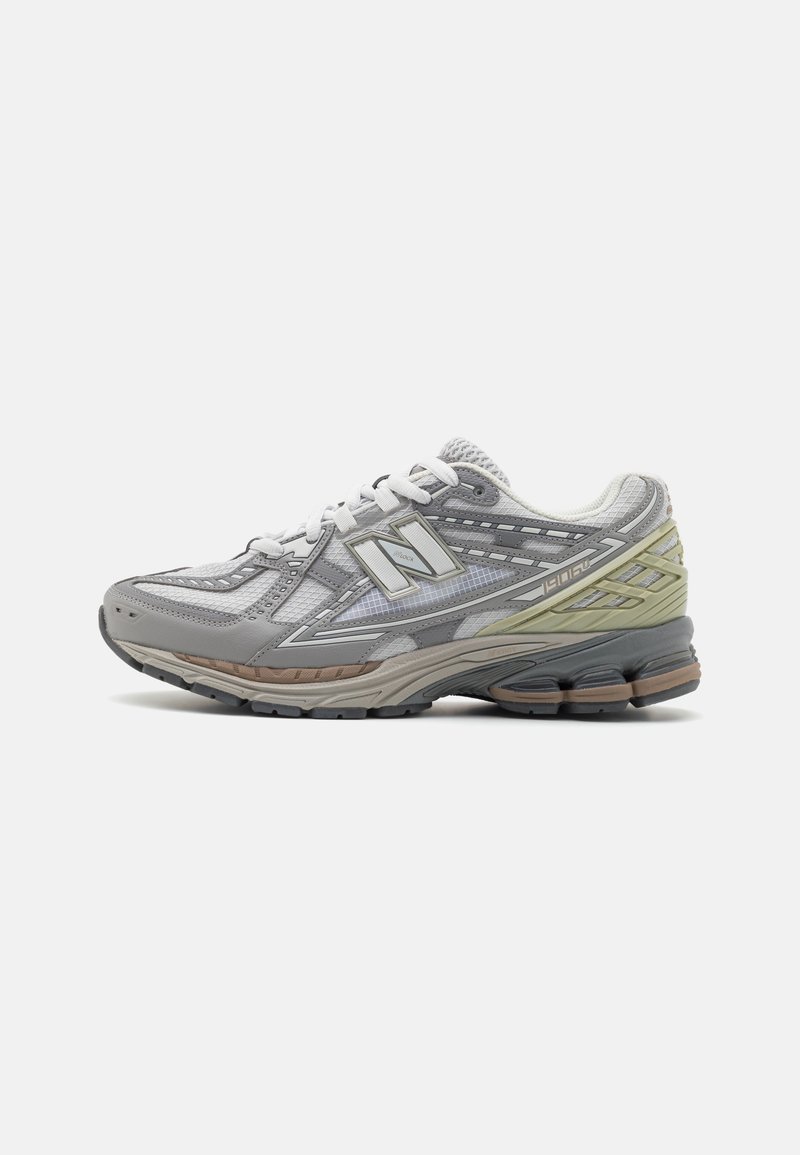 Chaussure de course New Balance grise et blanche avec empeigne en mesh, semelle rembourrée et accents vert clair et marron, vue du côté intérieur.