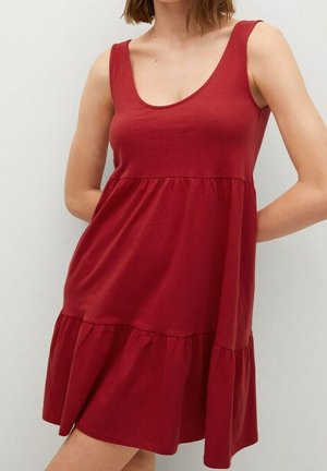 Mujer con un vestido rojo sin mangas hasta la rodilla, con escote redondo y detalle recogido en la cintura.