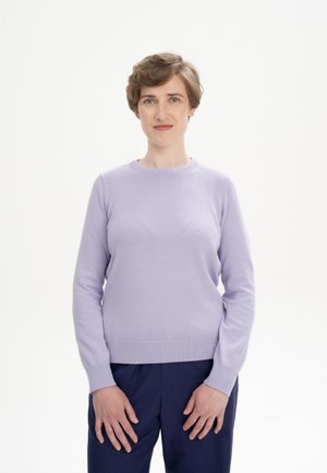 Pull en maille lavande avec un col rond et un ourlet à côtes, associé à un pantalon bleu marine, présenté sur un fond neutre.